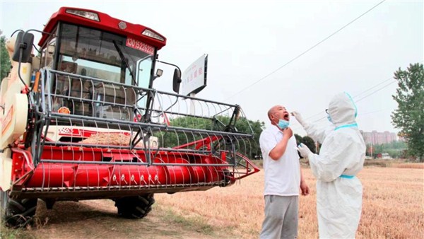 河南麦收新图景丨南阳市卧龙区：防疫人员田间地头为农机